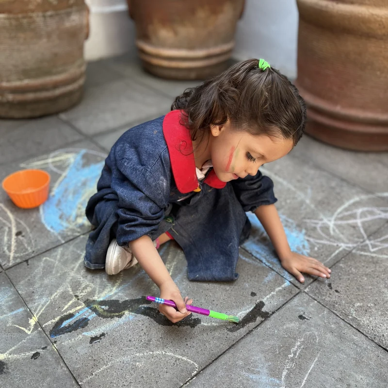 Niña de Pirulí pintando con gis en el piso